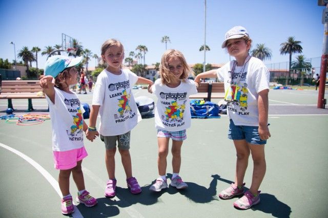 Four little girls wearing crayola shirts are standing on a basketball court