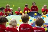 A group of children are playing with balloons on a parachute.