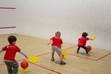 A group of children are playing squash on a court.