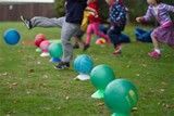 A group of children are playing with balloons in a field.