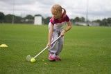 A young girl is playing golf on a lush green field.