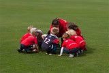 A group of children are sitting in a huddle on a field.