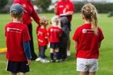 A group of children in red shirts are standing on a field.