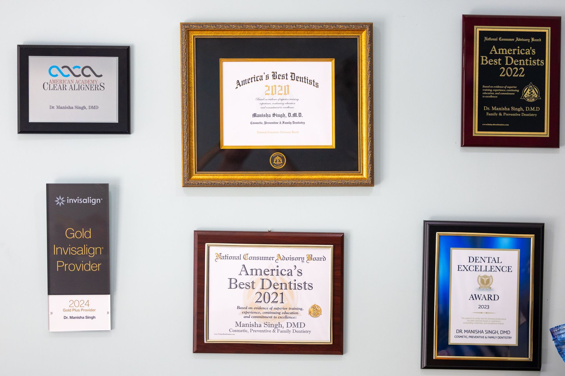 Wall with framed awards and plaques, likely in a dental office.