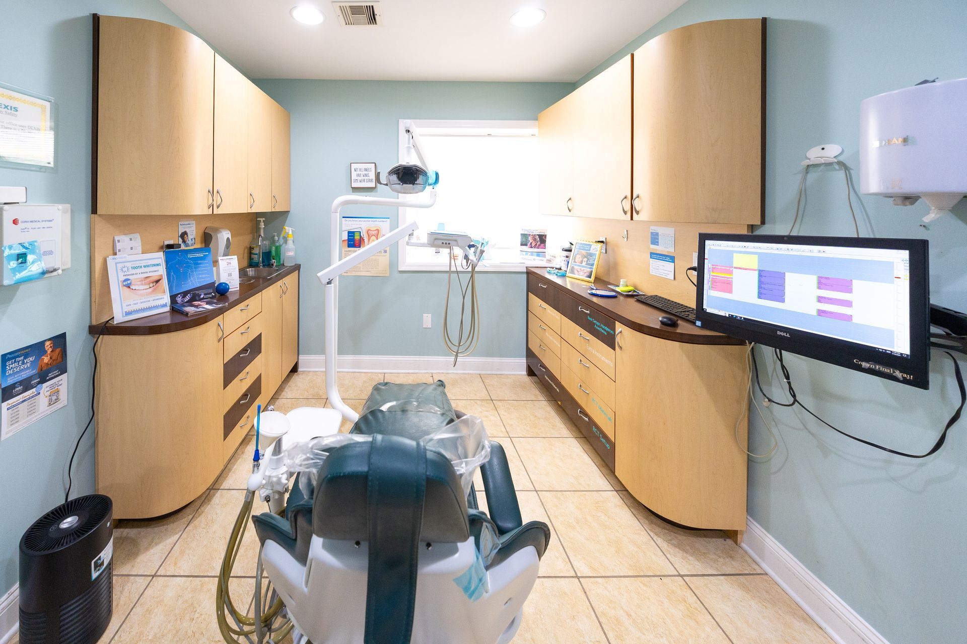 Dental office room with dental chair, cabinets, and a computer monitor.