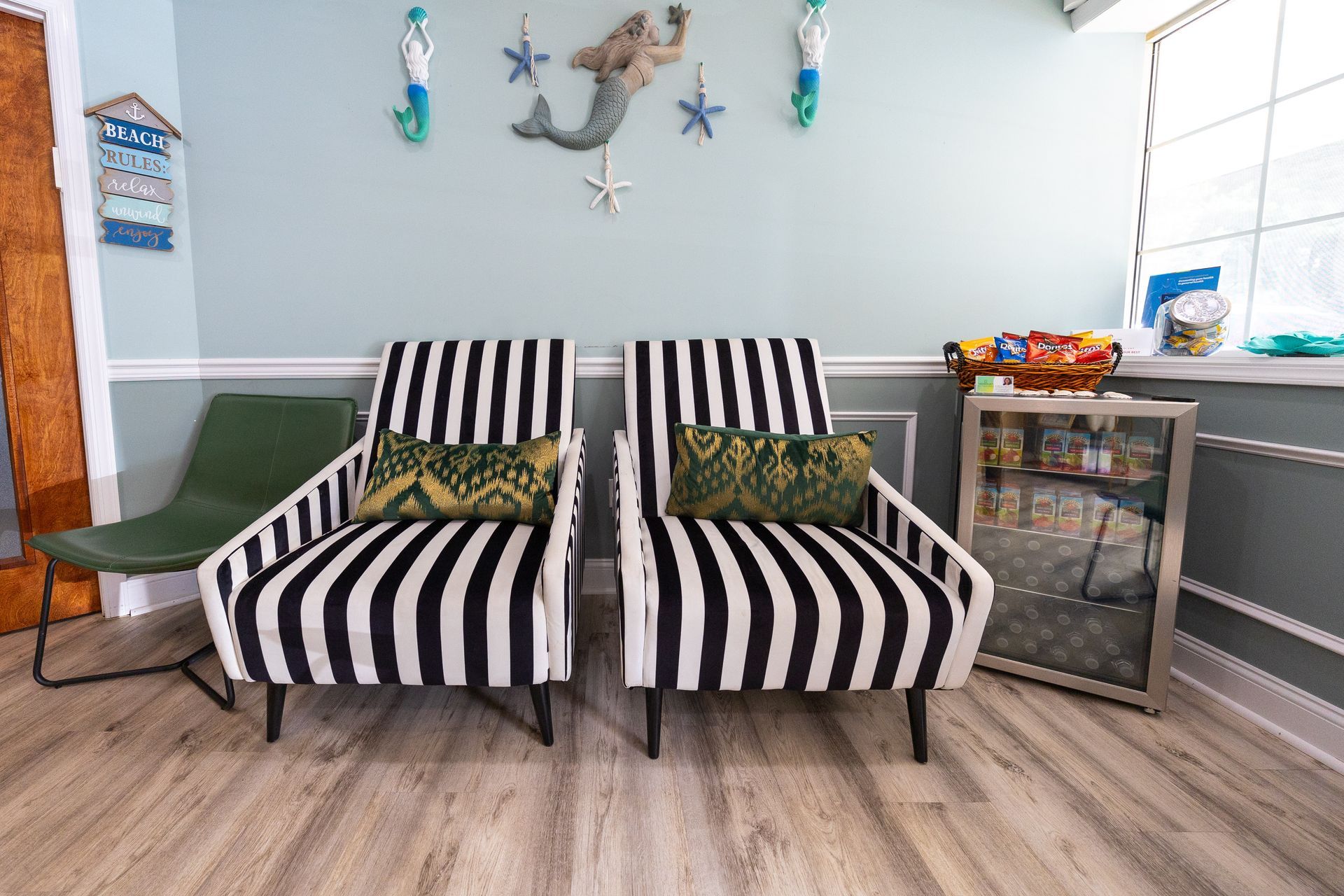 Waiting room with striped chairs, mermaid decor, and a small display case.