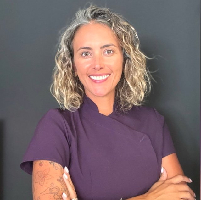 una donna sorride con le braccia incrociate e indossa una camicia viola Isabel proprietaria del centro estetico Bonita