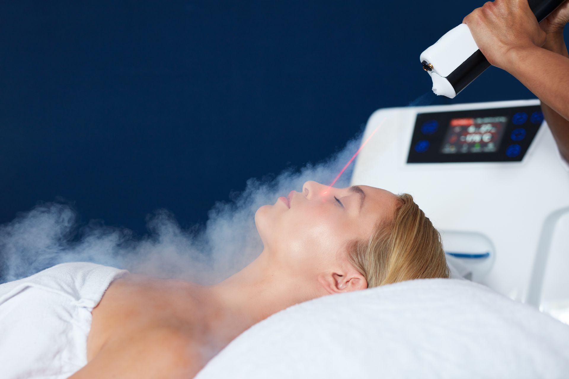 A woman is getting a cryotherapy treatment on her face.