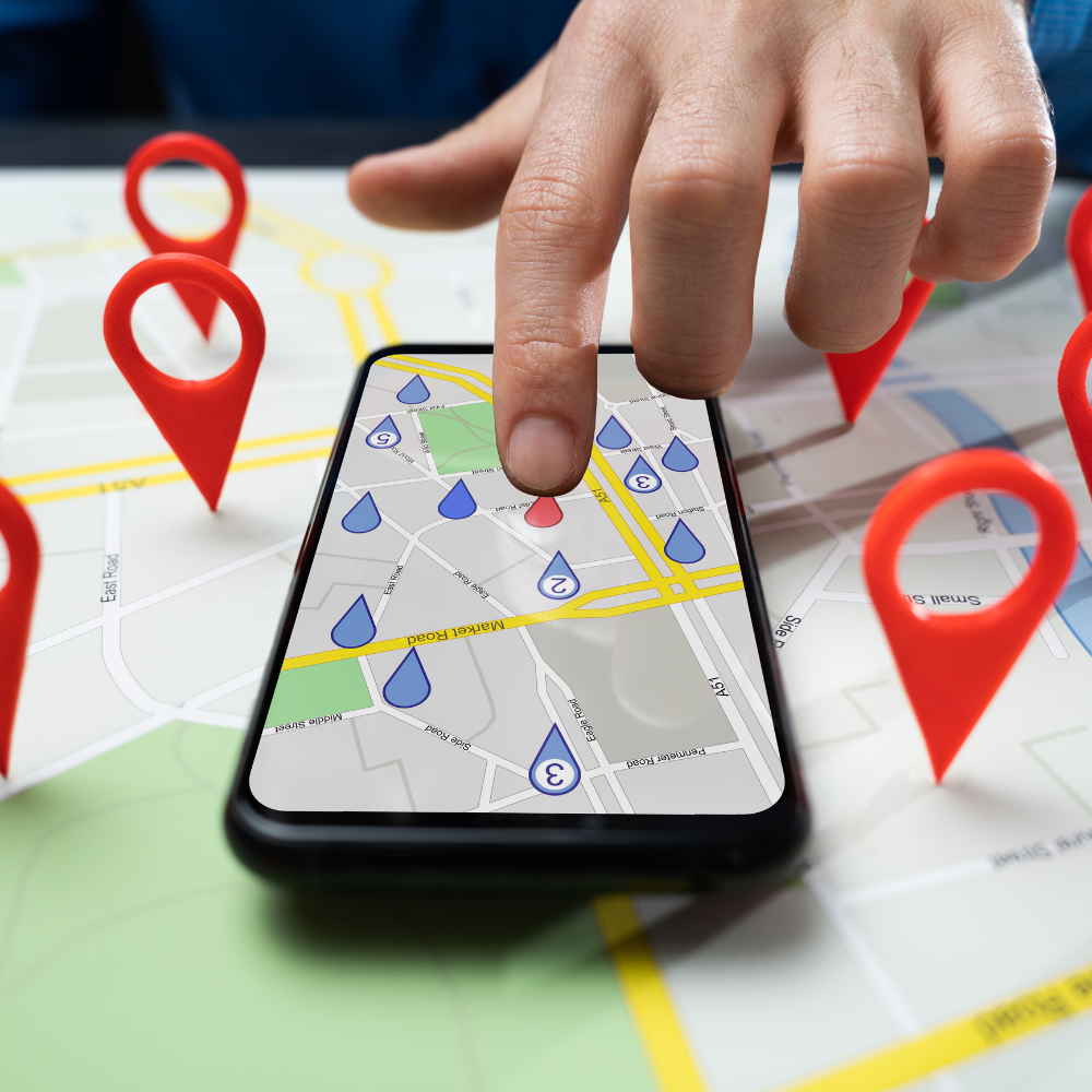A person is pointing at a cell phone on a map