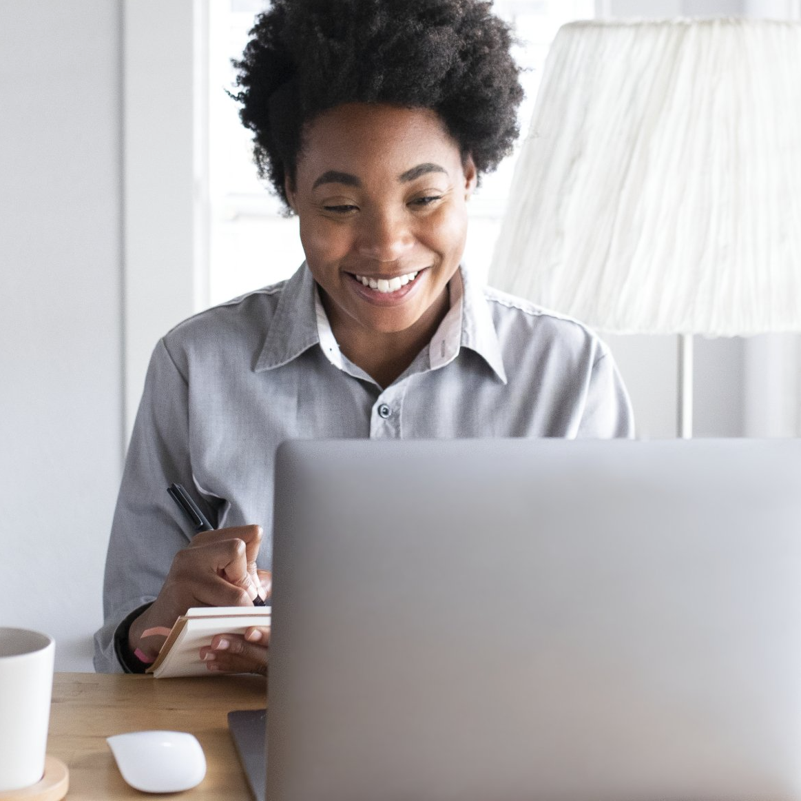 A woman is smiling while using a laptop computer