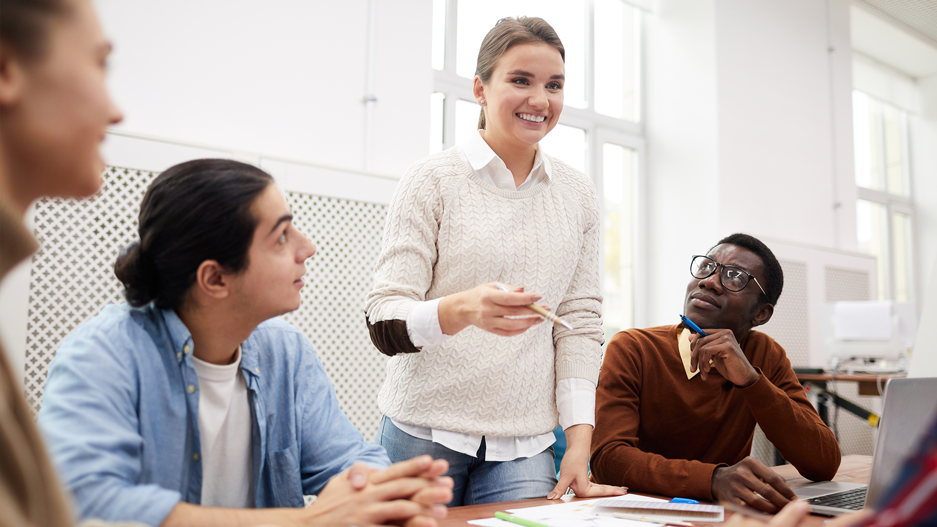 A group of people are sitting around a table having a meeting.