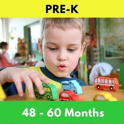 A young boy plays with wooden toy cars on a table in a classroom. The image is labeled 