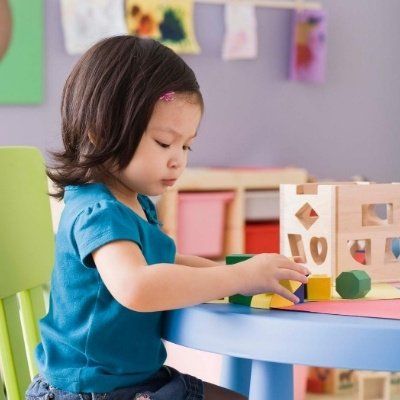 A little girl is sitting at a table playing with blocks and a box with the number 10 on it