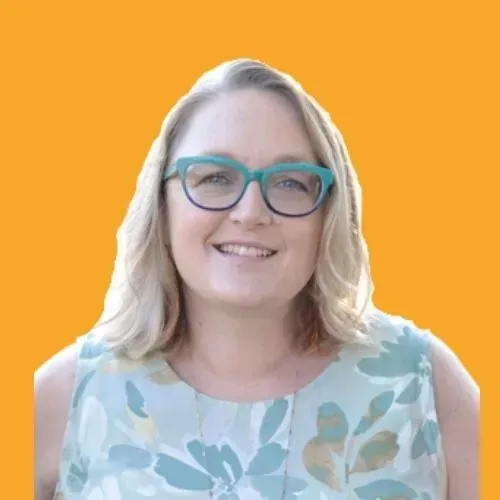 A woman wearing glasses and a floral shirt is smiling.