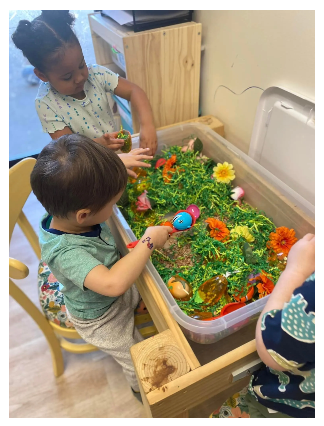 A group of children are sitting at a table in a classroom.