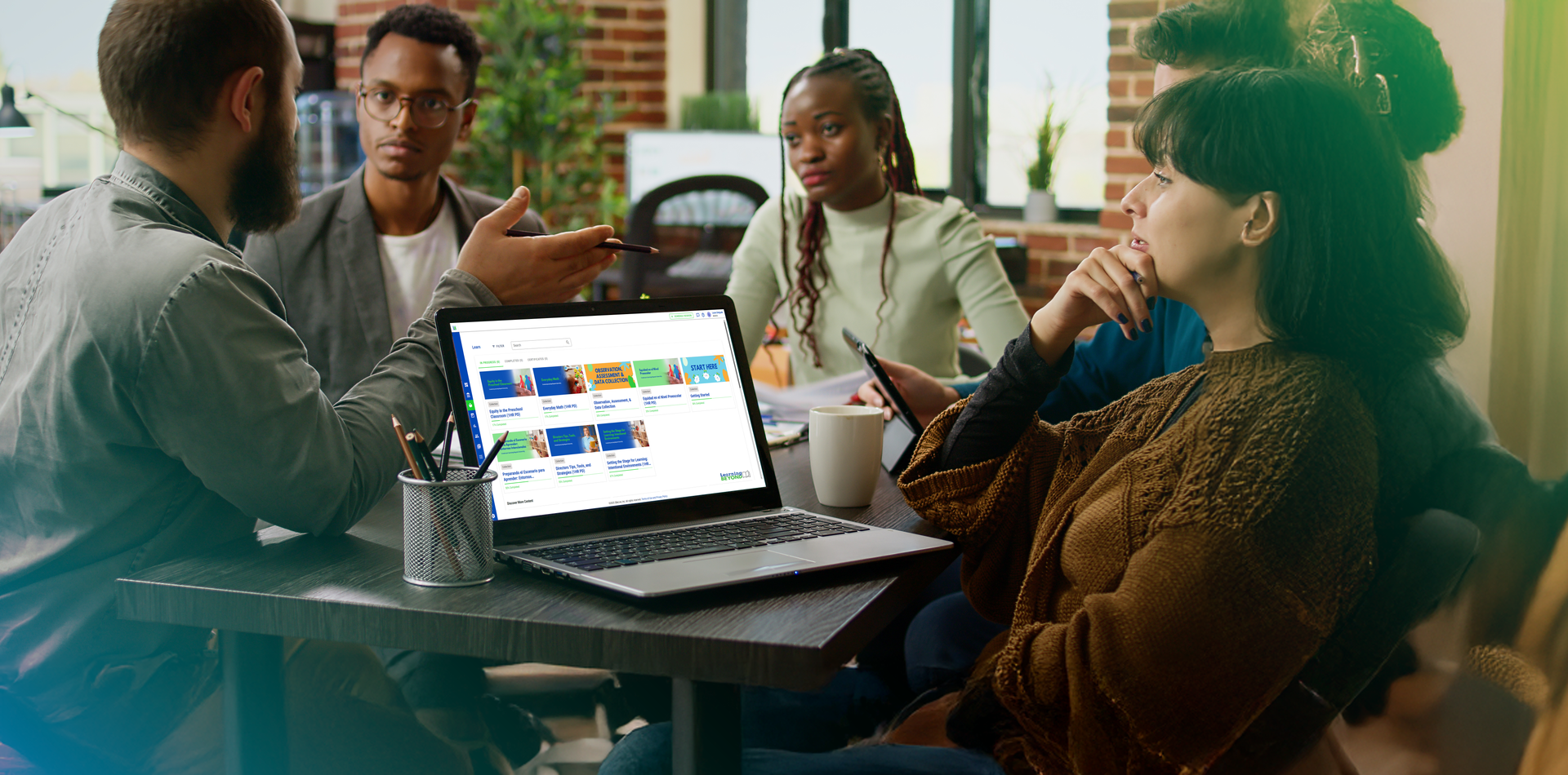A group of people are sitting around a table with a laptop computer.
