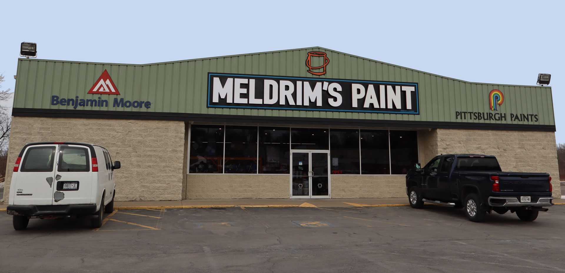 Two trucks are parked in front of a building that says meldrim 's paint