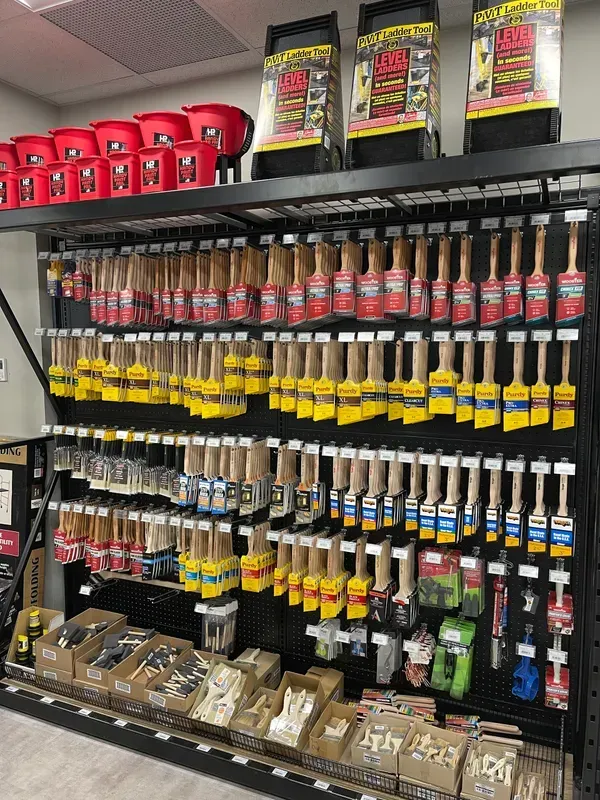 A store shelf filled with lots of paint brushes and buckets.