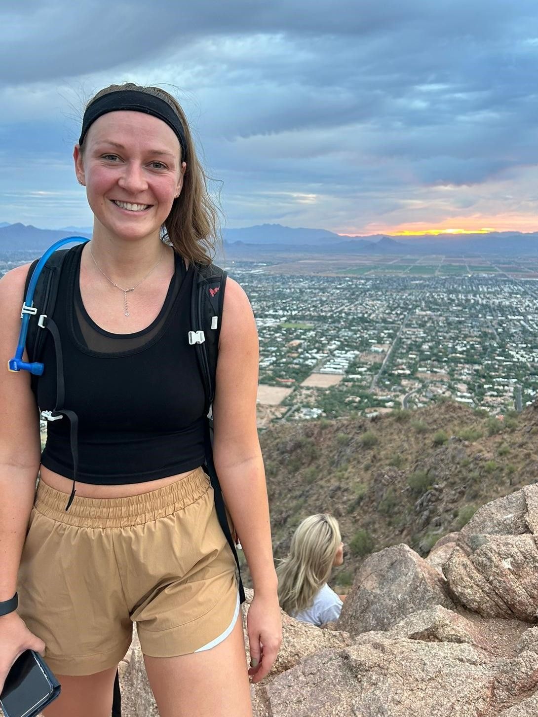 A woman is standing on top of a mountain with a backpack.