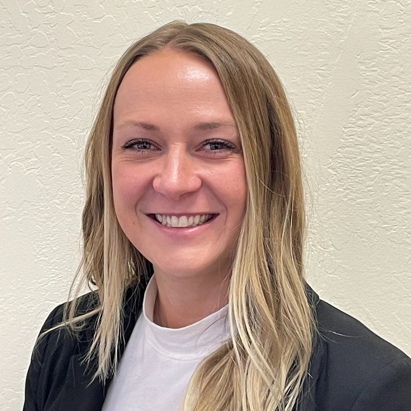 A woman in a black jacket and white shirt is smiling for the camera.