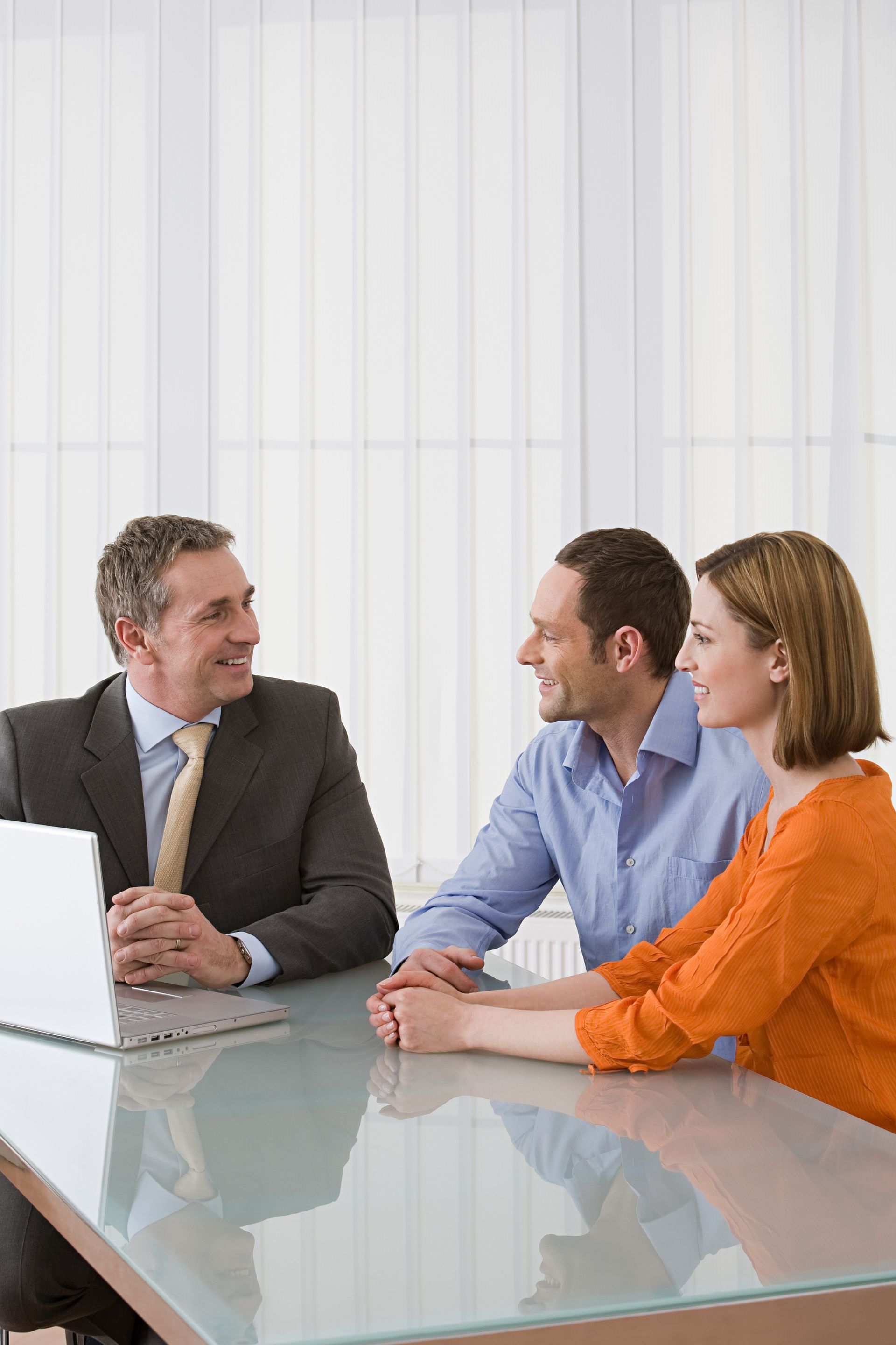 A man and two women are sitting at a table with a laptop.