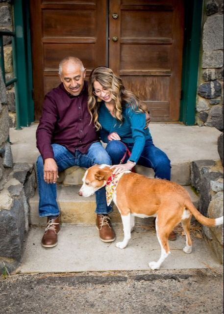 A man and a woman are sitting on steps with a dog.