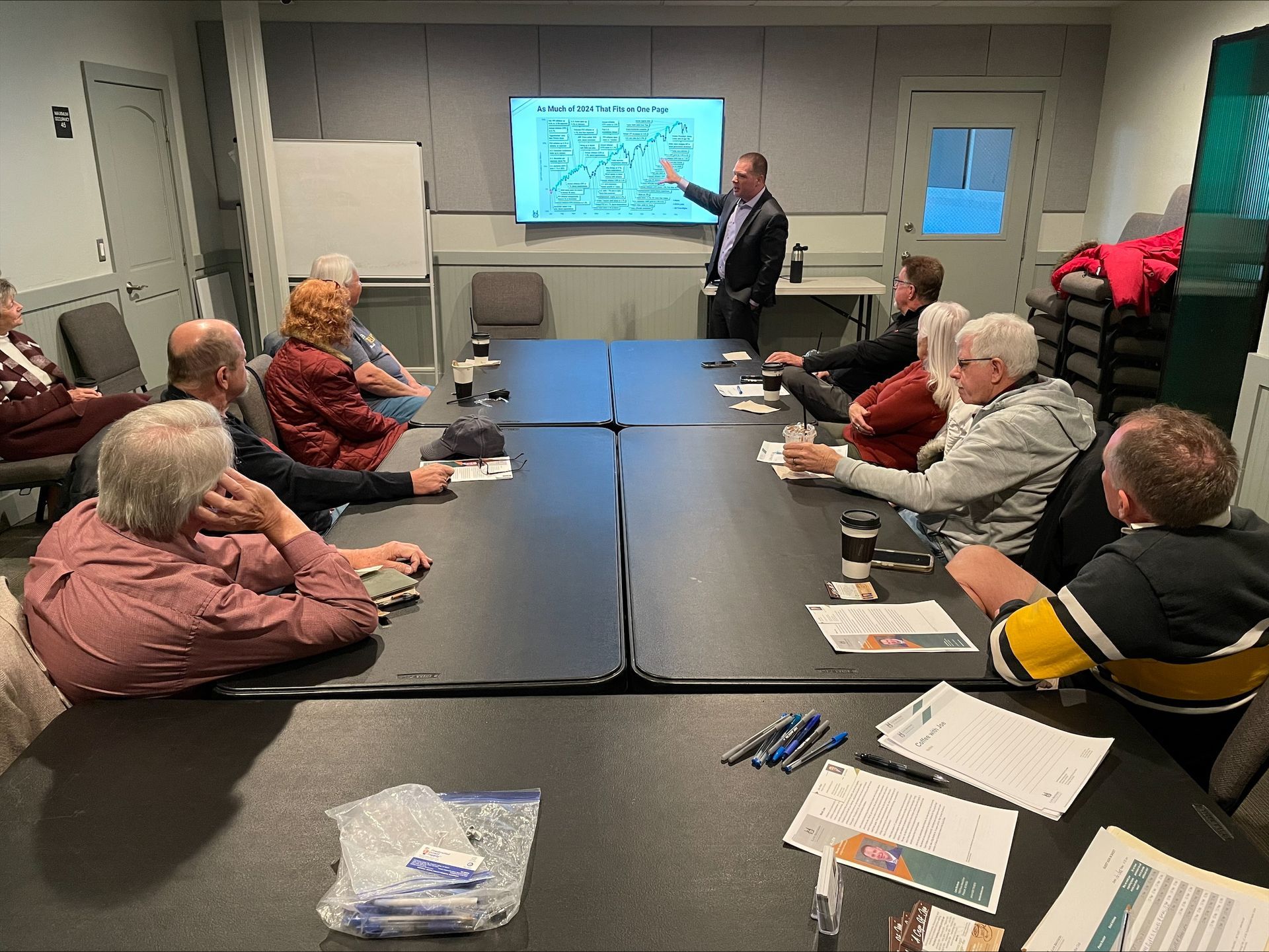 A man is giving a presentation to a group of people sitting around a table.