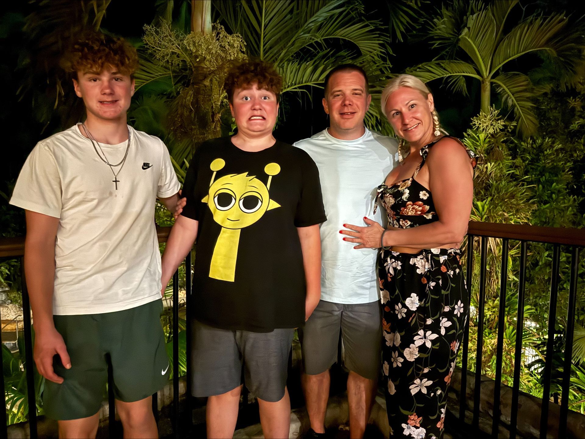 A family posing for a picture on a balcony at night