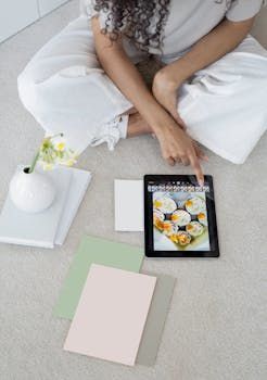 Eine Frau sitzt auf dem Boden und starrt auf ein Tablet mit einem Bild von Muffins darauf.