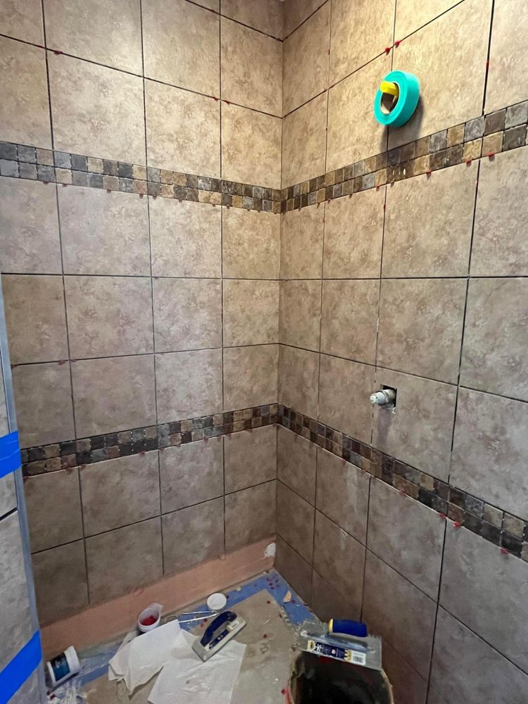 A bathroom with tiles being installed on the walls and floor.