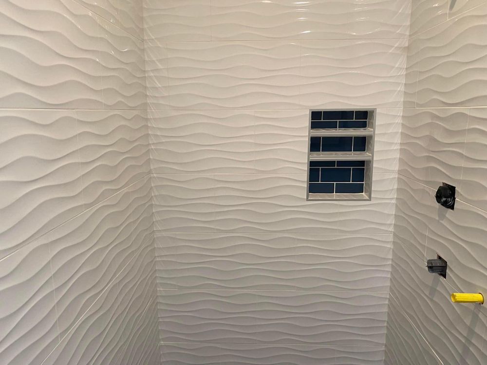 A shower with white tiles and a blue tile niche.