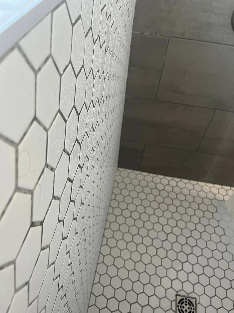 A bathroom with white hexagon tiles and a drain
