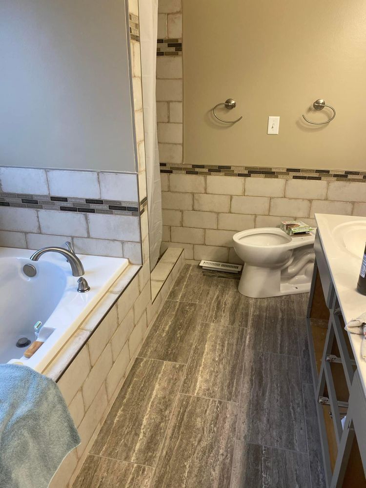 A bathroom with a tub , toilet , sink and mirror.