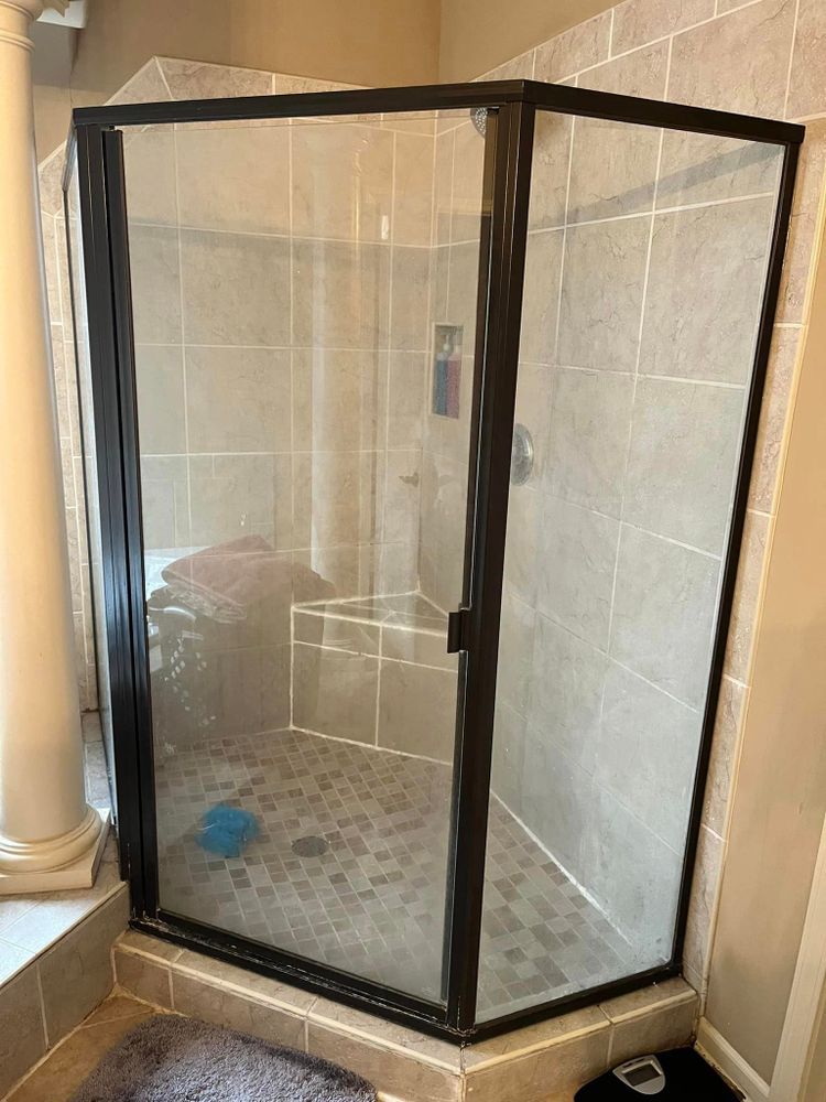 A bathroom with a walk in shower with a black frame.