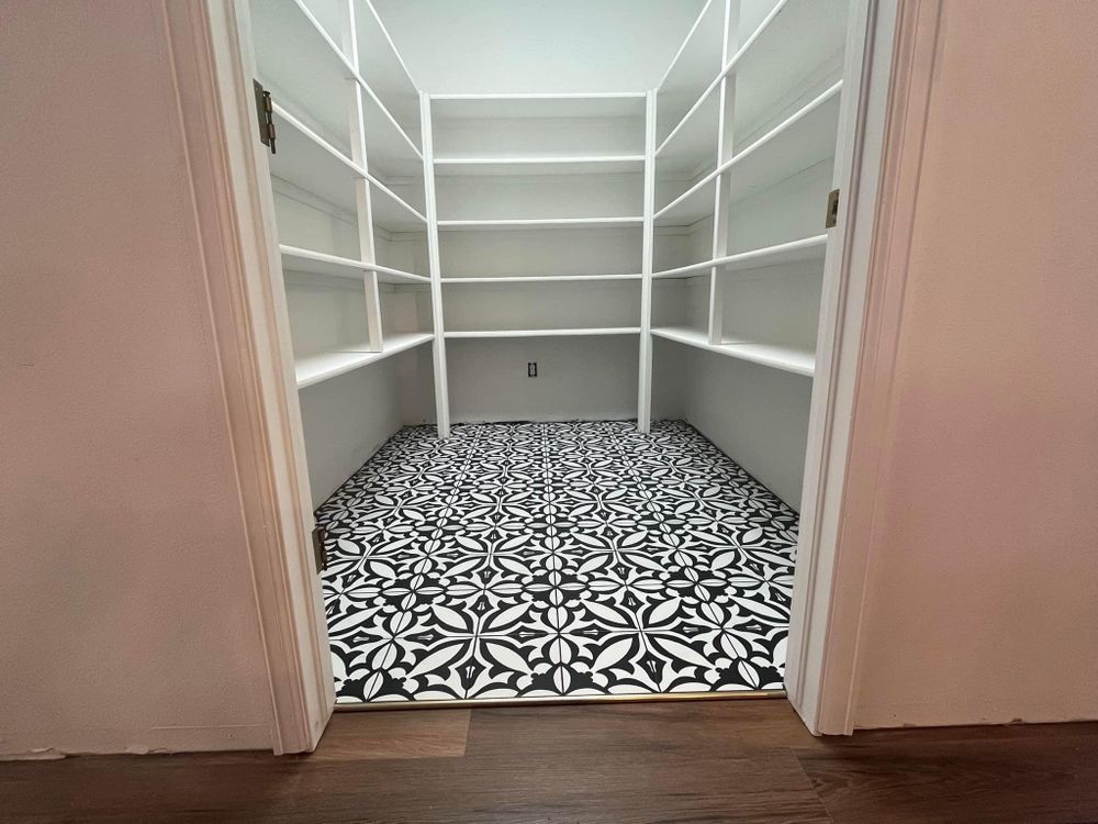 A walk in pantry with black and white tile floors and shelves.