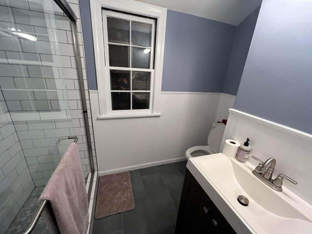 A bathroom with a sink , toilet , shower and window