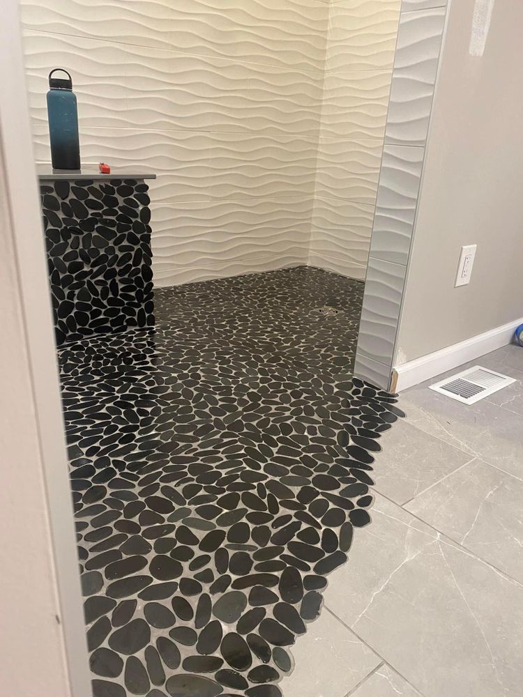 A bathroom with a walk in shower and a black and white tile floor.