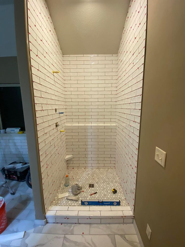 A bathroom with white brick tiles and a walk in shower.