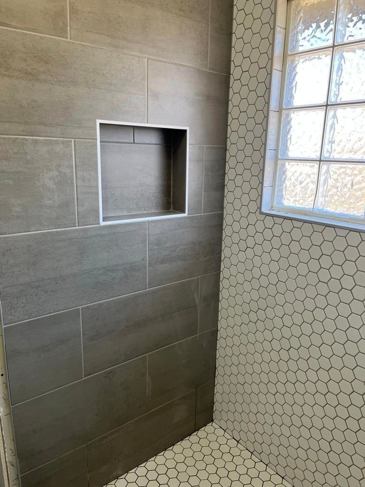 A shower with a window and a niche in the wall.