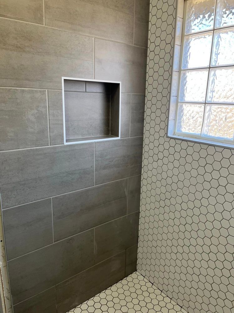 A shower with a window and a niche in the wall.