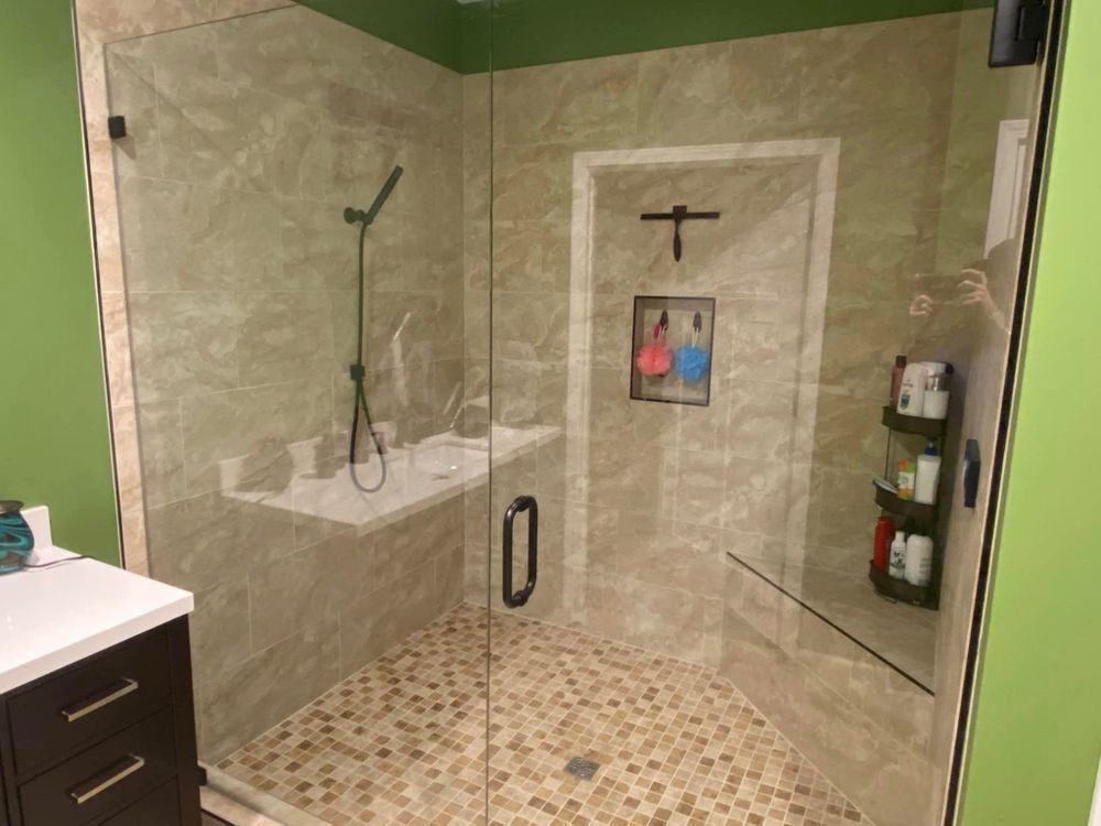 A bathroom with a walk in shower with a glass door.