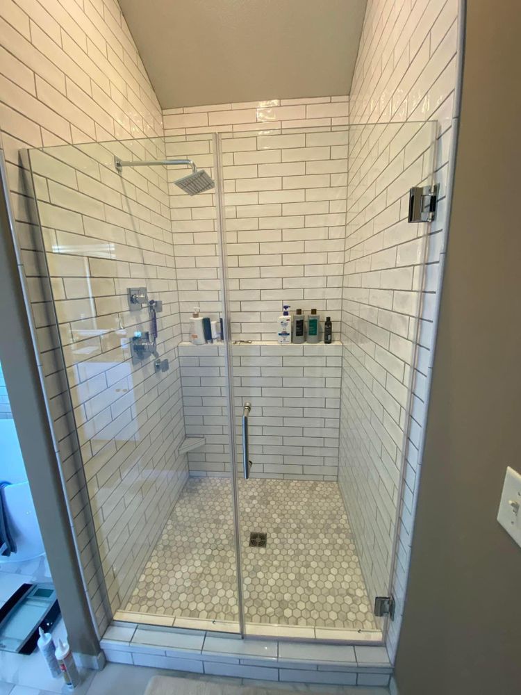 A bathroom with white brick walls and a walk in shower with a glass door.