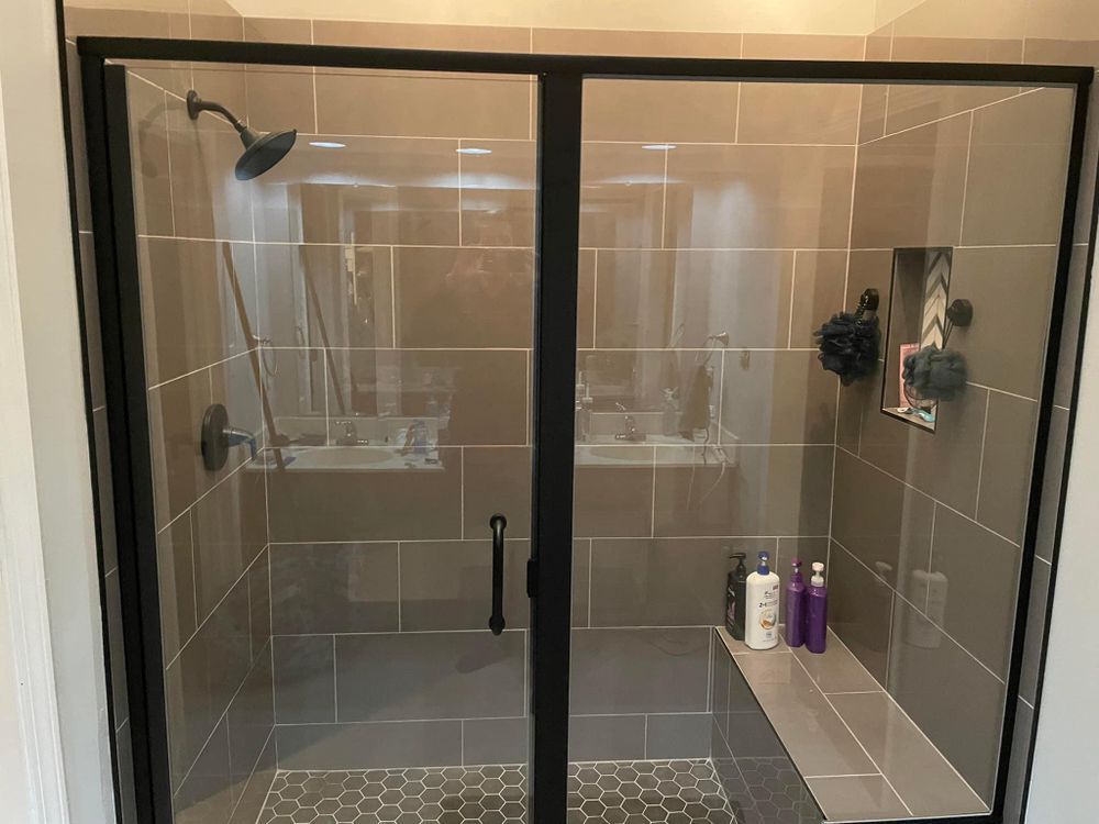 A bathroom with a walk in shower with a glass door.