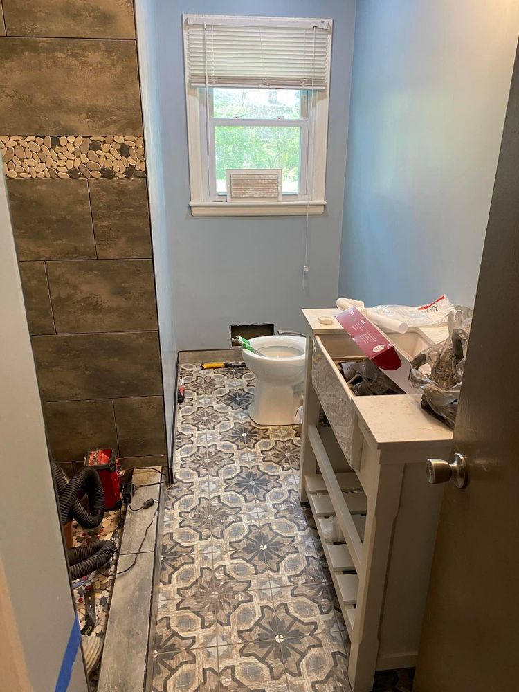A bathroom under construction with a toilet , sink , and window.