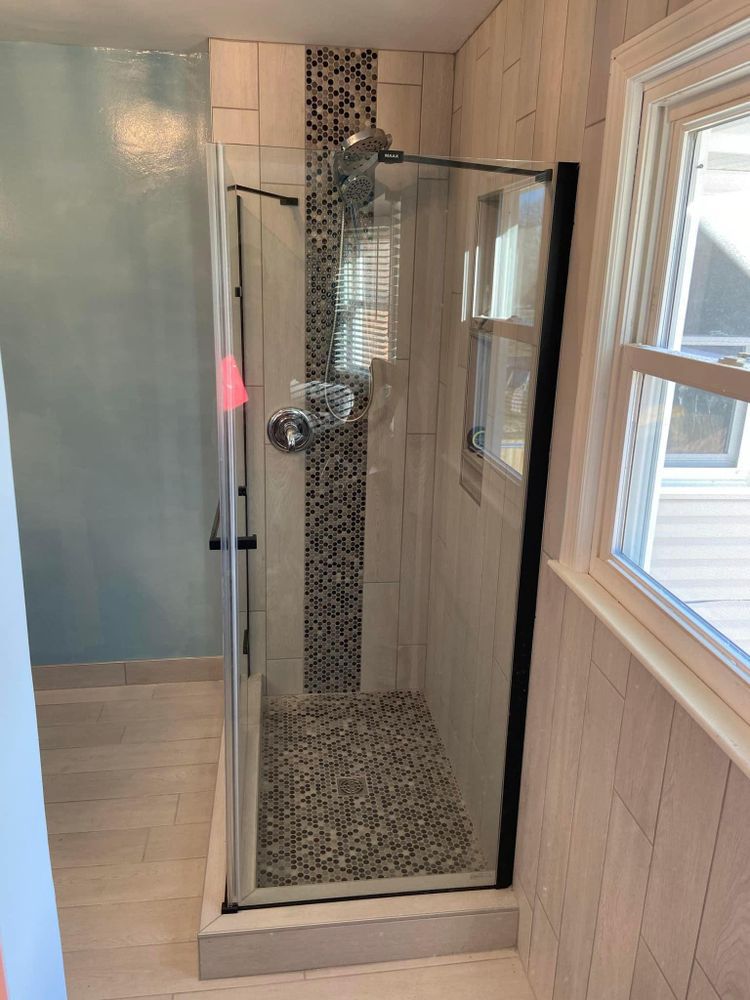 A bathroom with a walk in shower and a window.