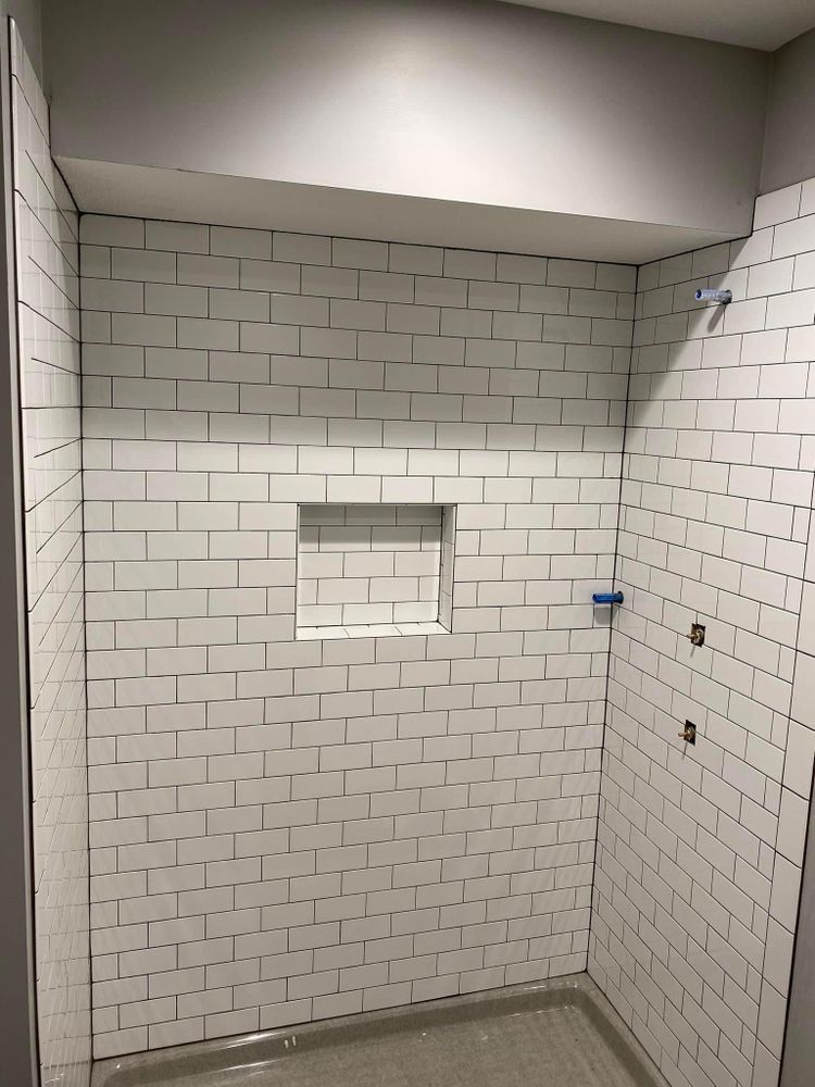 A bathroom with white brick walls and a shower stall.