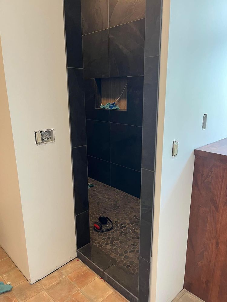 A doorway leading into a bathroom with black tiles.
