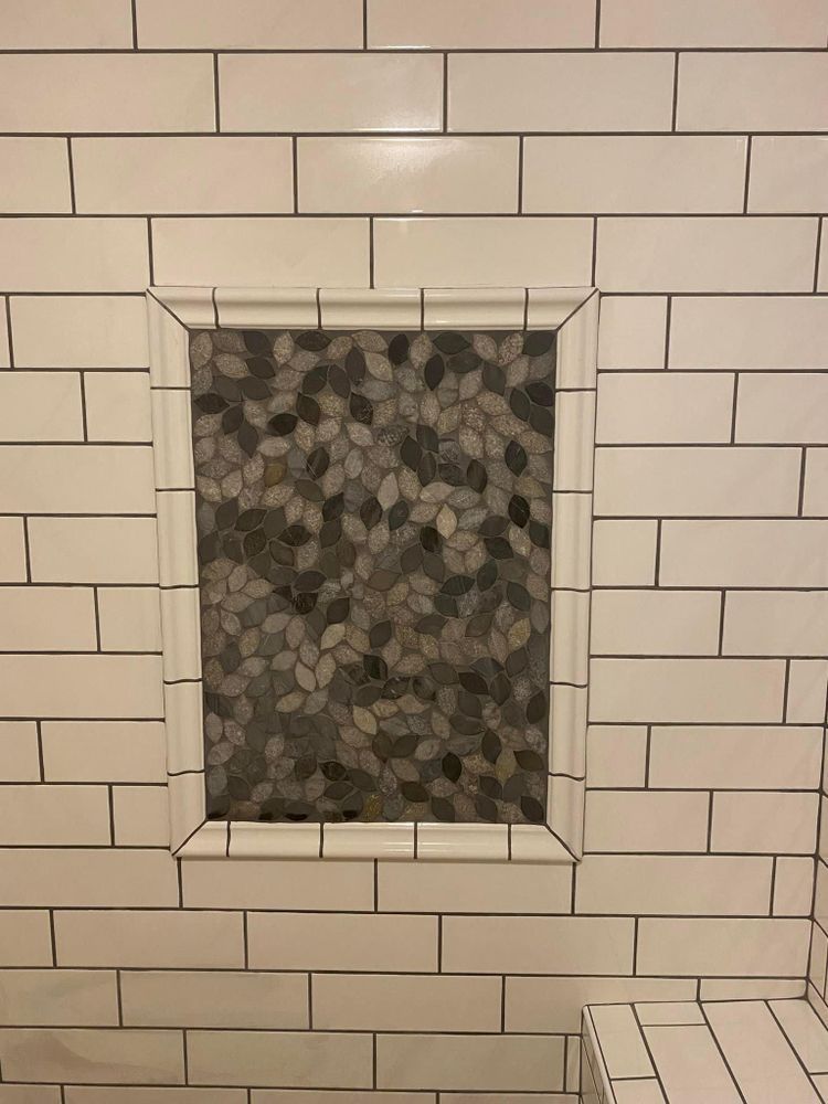 A shower stall with a tiled niche in the wall.