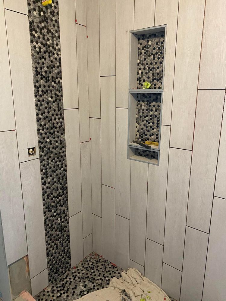 A bathroom with white tiles and a mosaic shower.