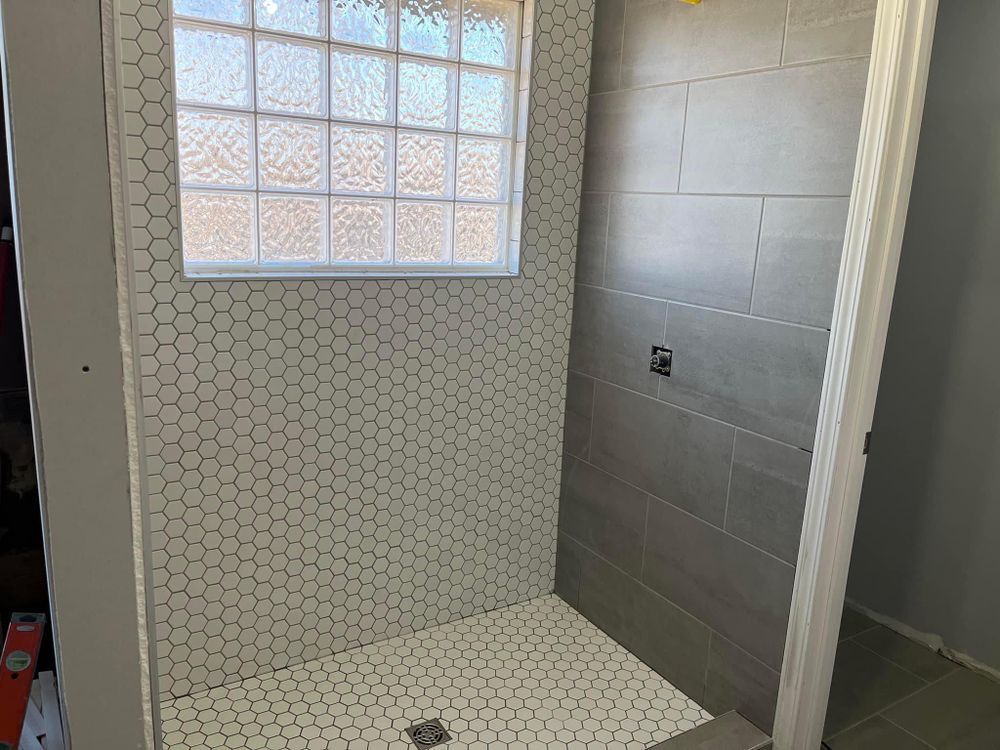 A bathroom with a walk in shower and a window.